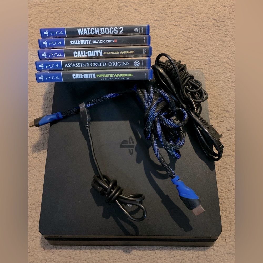 Sony PlayStation 4 Slim Console - 1 TB storage with multiple games and chords.